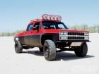 Red off-road pickup truck with light bar on roof, modified for desert racing