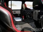 Interior of a modified off-road vehicle with racing seats, roll cage, and dashboard electronics
