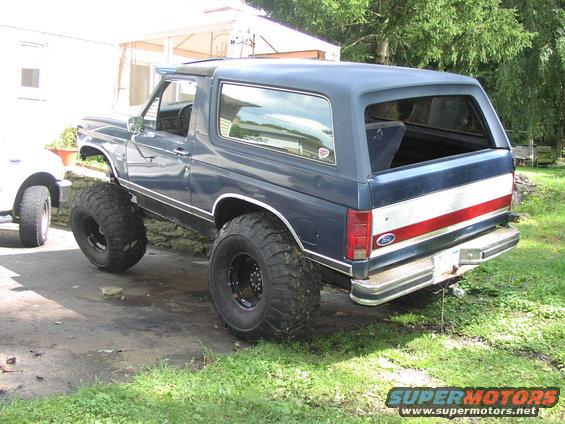 Blue Ford Bronco with large tires parked outside