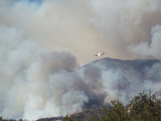 Firefighting air tanker flying over smoky mountains during a wildfire