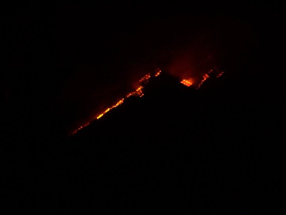 Hillside burning with orange flames against a black night sky