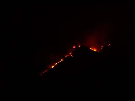 Hillside on fire at night with glowing embers