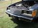 1985 Ford LTD - Front view of a dark blue Ford car with the hood open, revealing the engine compartment and a chrome grille.