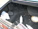 1985 Ford LTD - The trunk interior of a vehicle, showing a spare tire, cleaning supplies, and debris.