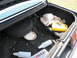 1985 Ford LTD - Interior of a car trunk containing various items including a plate, bottles, and a yellow jug.