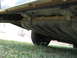 1985 Ford LTD - The underside of a vehicle is visible, including the fuel tank and a tire, against a backdrop of grass and a house.