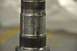 1996 Ford Bronco - A close-up view of a metal spindle shows wear and tear, indicating it is a mechanical part.