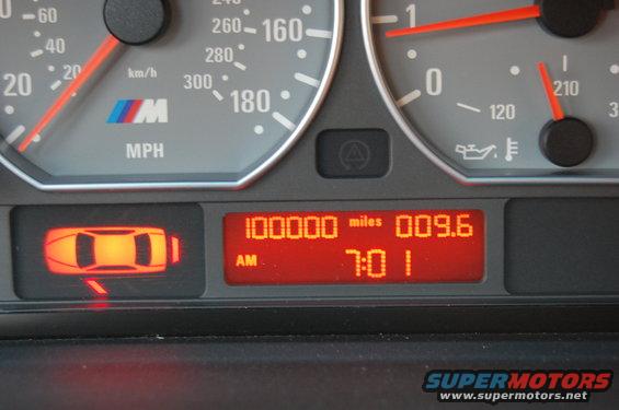 BMW M3 instrument cluster showing 100000 miles, 009.6, 7:01 AM, and an illuminated door warning light