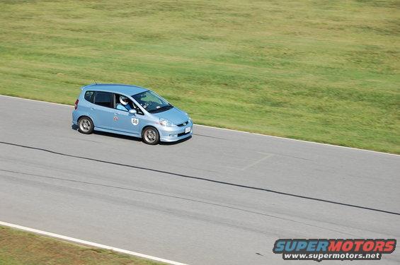 Blue Honda Fit with number 58 on door driving on a race track