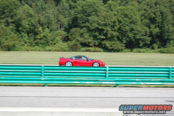 Red sports car with a black roof and a rear spoiler on a race track