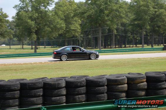 Black 2002 BMW M3 coupe on racetrack, side view