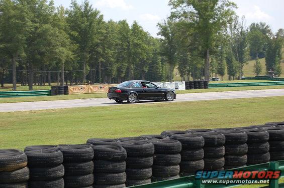 Black 2002 BMW M3 coupe on a race track, side view