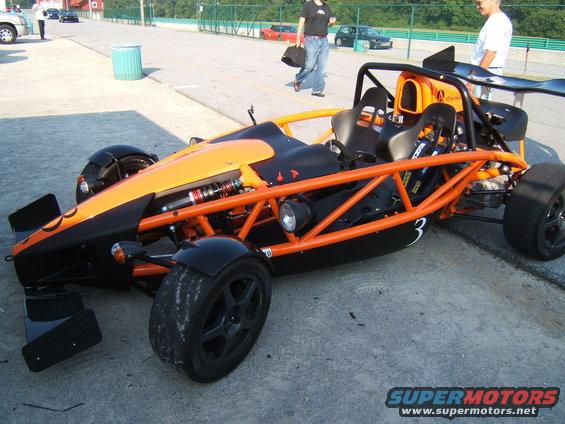 Orange and black Ariel Atom race car with roll cage and racing seats