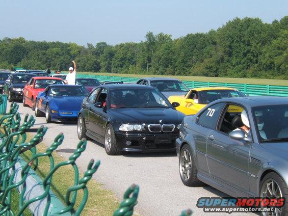 Black BMW M3 with racing stripes, front view, on a track
