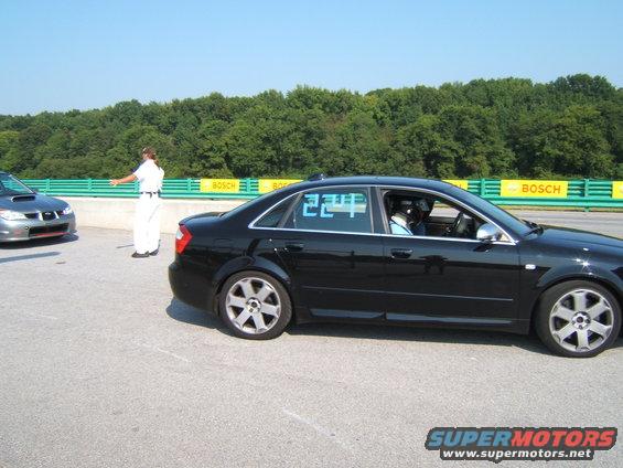 Black sedan with blue racing numbers on window, side view