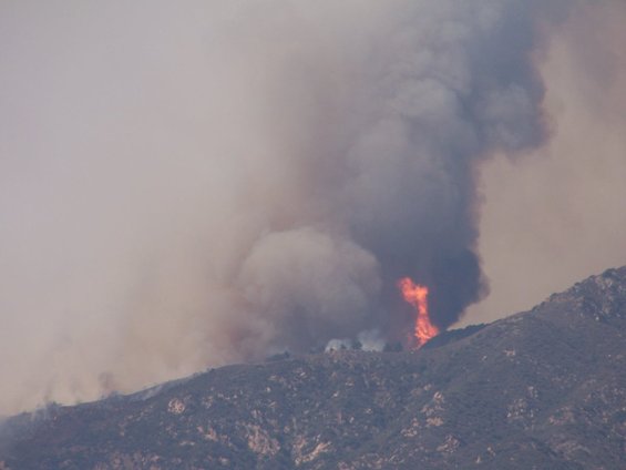 Mountain hillside engulfed in flames and smoke