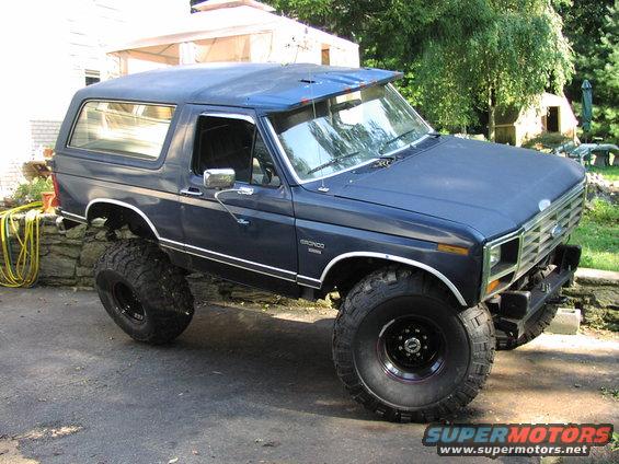 Blue Ford Bronco with lifted suspension and large tires, parked on asphalt
