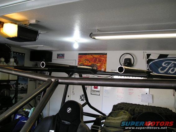 Roll cage and racing seat inside an off-road vehicle; Ford logo flag on wall