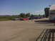 2005 Ford F-250 - Cars are parked in a lot outside a building with racing graphics under a clear sky.