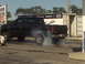 2005 Ford F-250 - A black 2005 Ford F-250 performs a burnout, emitting smoke from its tires.