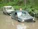 1993 Jeep Cherokee - Two Jeeps are submerged in muddy water with trees and foliage in the background.