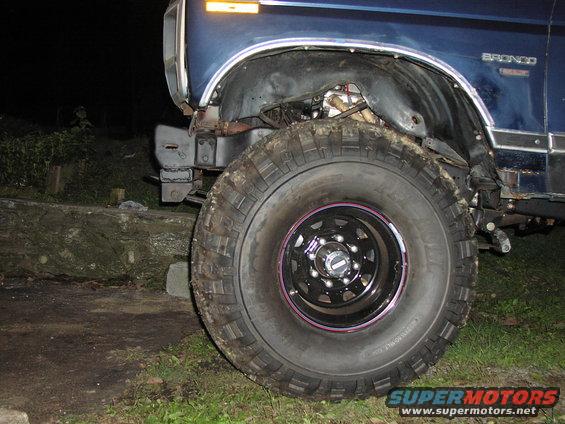1986 Ford Bronco front fender, wheel, and tire. Blue paint visible
