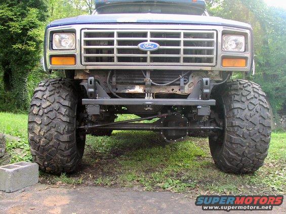 Front view of a lifted Ford truck with oversized tires and a chrome grille. The Ford logo is visible on the grille
