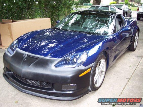 Blue Corvette with a primer-gray front bumper, parked outside with other cars behind it