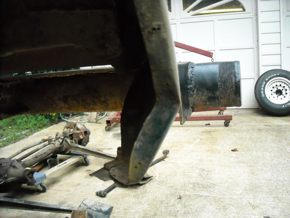 Close-up of rusted truck frame and suspension components with a tire in the background