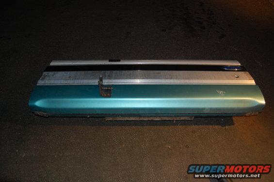Teal door panel with chrome trim and a Ford emblem