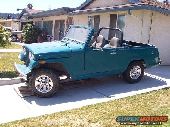 Teal 1970 Jeep Jeepster convertible with roll bar parked in driveway