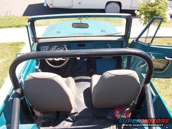 Interior of a teal Jeep with tan seats, roll bar, and dashboard visible. Doors are open