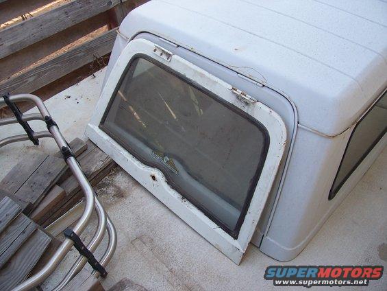 White Jeep hardtop with open side window, resting on wooden planks