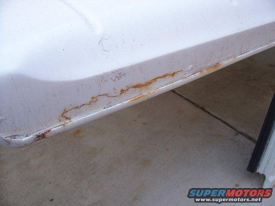 White vehicle lower body panel showing extensive rust along the seam