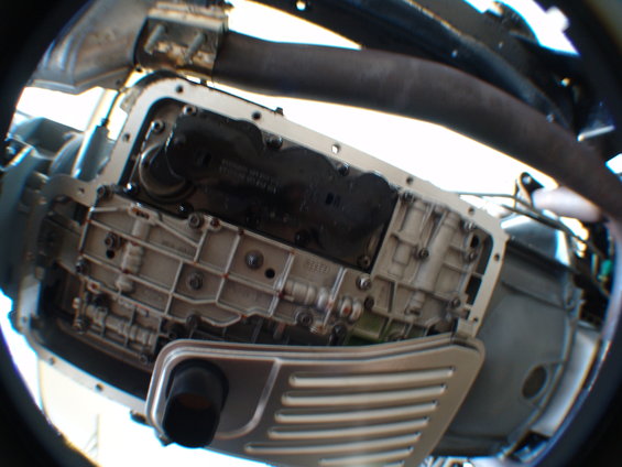 Close-up of a transmission pan with filter removed, showing internal components and some fluid
