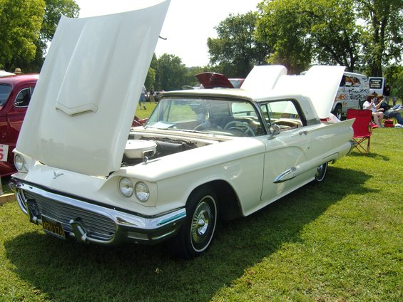 White 1958 Ford Thunderbird with hood and trunk open, parked on grass at an outdoor event