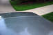 1995 Ford Bronco - Close-up of a car's roofline and antenna against a backdrop of grass and pavement.