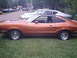 1978 Ford Mustang II - Side view of an orange coupe with a black t-top and louvers on the rear quarter window.