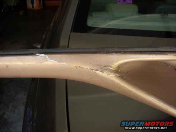 Close-up of peeling paint and damage on a car's door trim piece