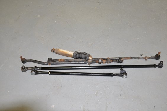 Steering linkage and shock absorber parts laid out on a gray floor