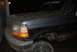 1995 Ford Bronco - A dirty black Ford Bronco is parked in a garage at night, viewed from the front-right.