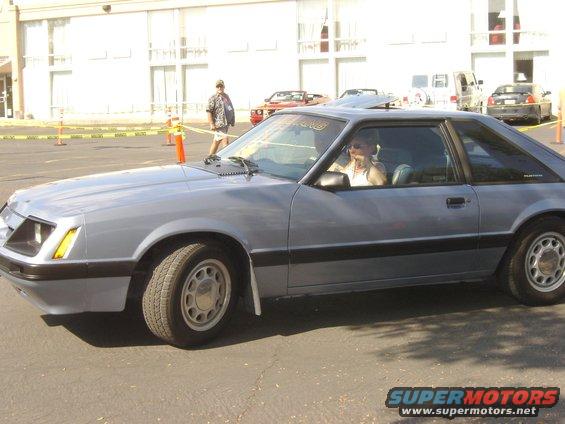 Gray coupe with a sunroof and a person driving, seen from the side