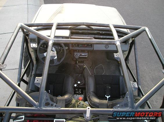 Interior of a 1986 Toyota Hilux with a custom roll cage, racing seats, and aftermarket stereo