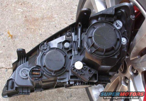 Rear view of a car headlight assembly with electrical connectors and internal components visible
