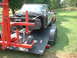 1964 Ford Fairlane - A car body, missing its engine and front clip, is loaded onto a trailer for transport.