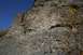 1990 Chevrolet Suburban - A rocky cliff face under a bright blue sky, with autumn foliage visible on the right side.