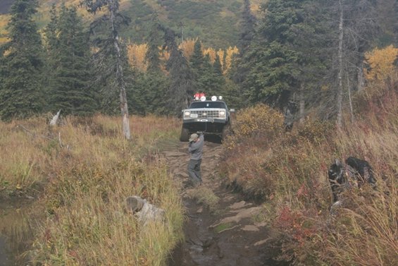 1990 Chevrolet Suburban climbing a muddy trail with off-road lights