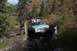 1990 Chevrolet Suburban - An off-road vehicle tackles a challenging, muddy path surrounded by autumn foliage and trees.