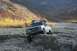 1990 Chevrolet Suburban - A white Chevrolet K5 Blazer tackles a challenging off-road terrain in a mountainous, autumnal landscape.