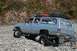 1990 Chevrolet Suburban - A modified SUV navigates a rocky, off-road path with a person smiling inside.